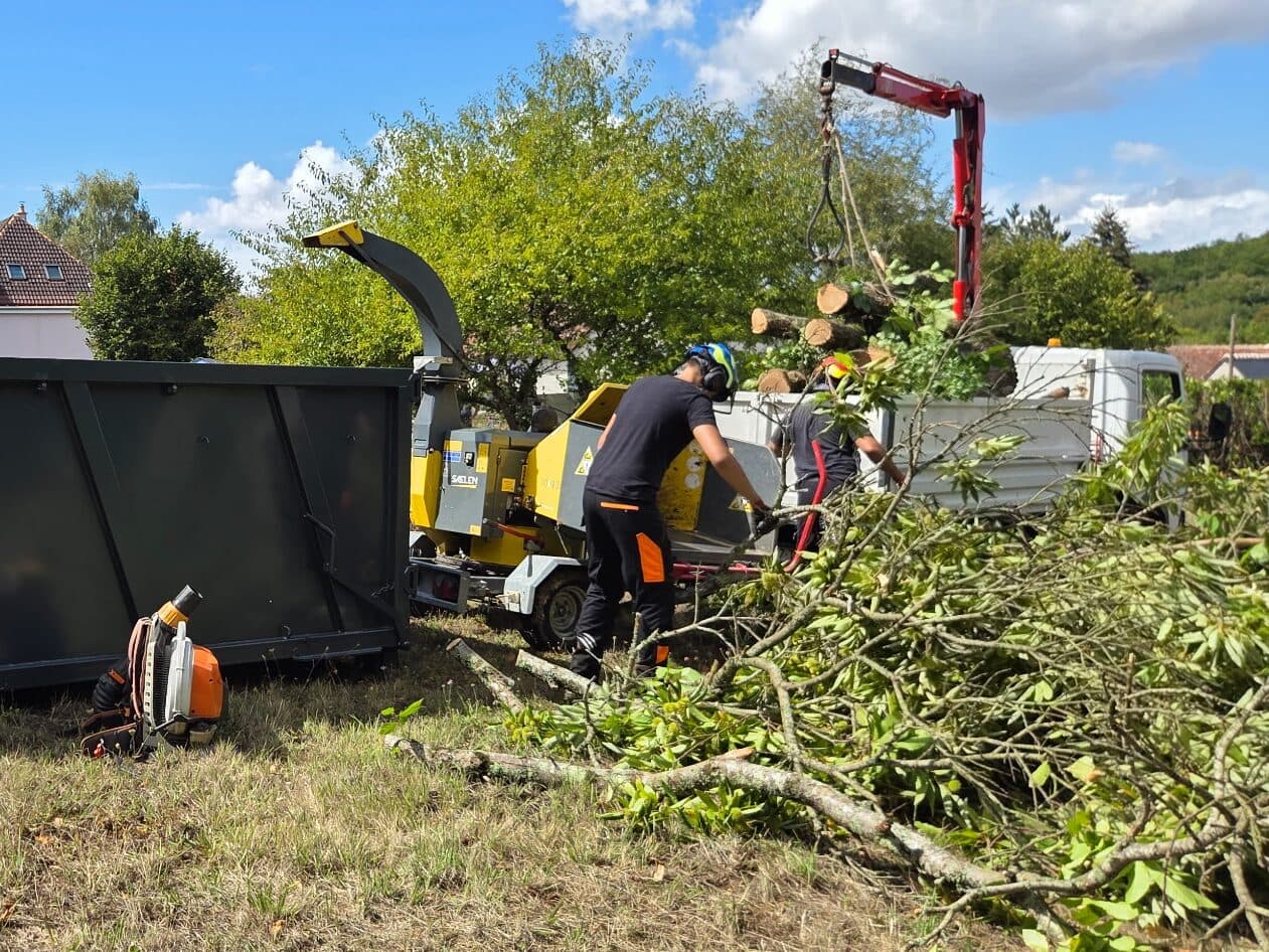 Branches passées au broyeur sur le chantier, à côté du camion-grue chargé de tronçons
